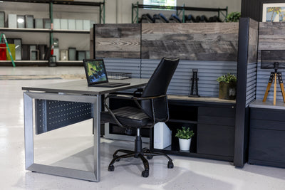 Modern office desk with a chair and computer setup in a room with shelves and decor.